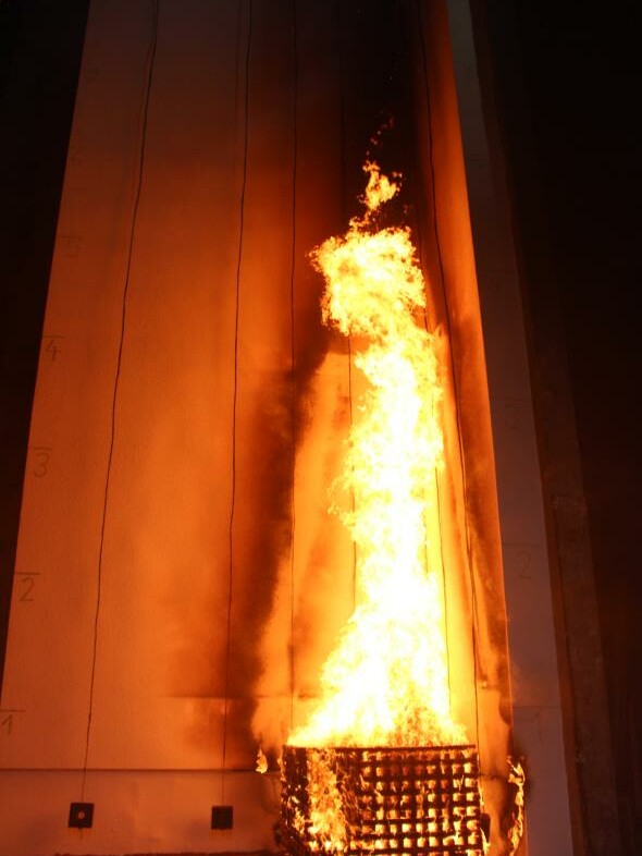 Fassadenprüfstand während einer Prüfung im Brandschutz mit Holzkrippen im Vordergrund