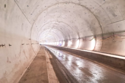 Blick in eine im Rohbau befindliche Tunnelröhre mit Baustellenbeleuchtung