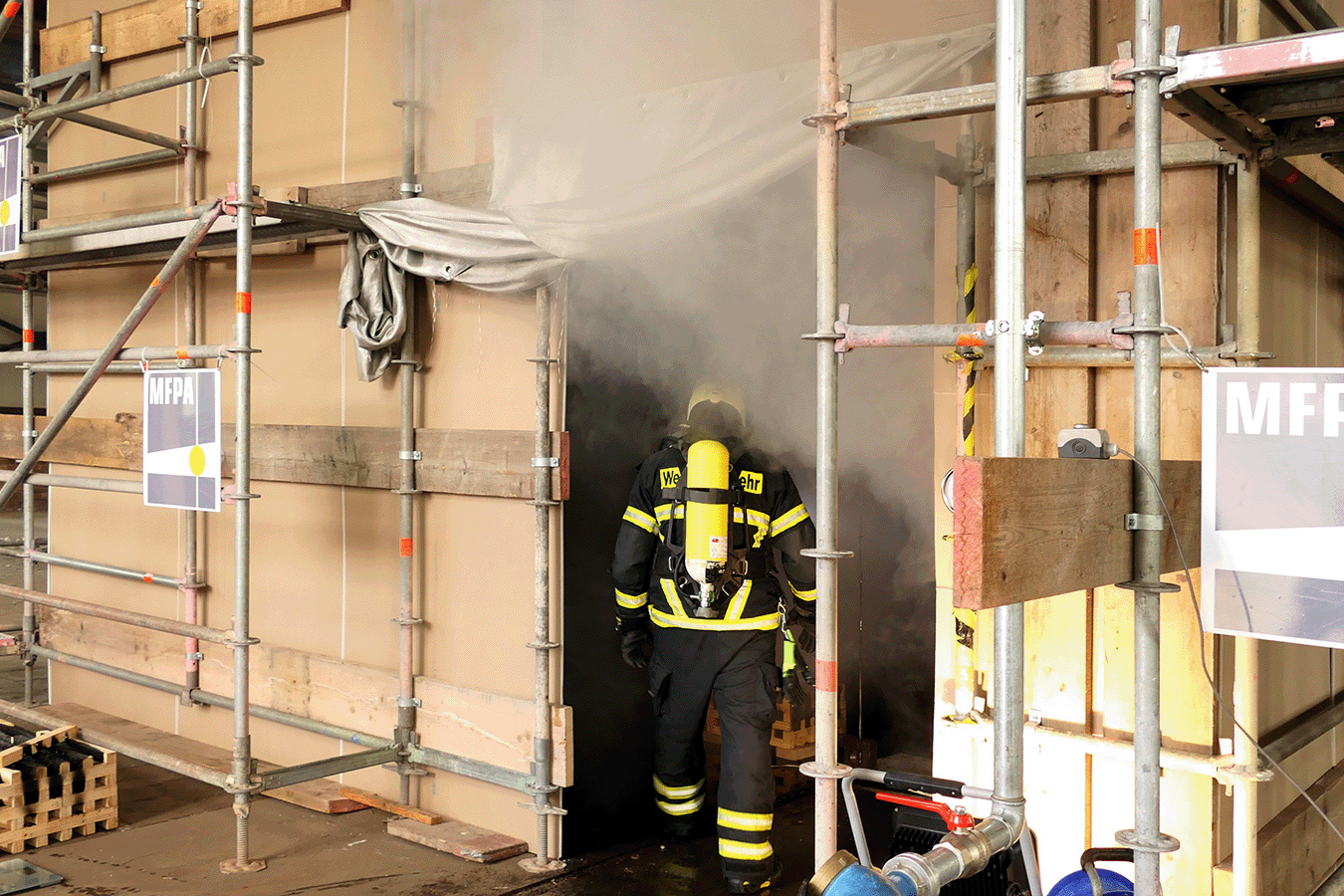 Brandversuche zur Löschwirkung einer Feuerlöschanlage mit einem Feuerwehrmann der einen rauchgefüllten Raum betritt
