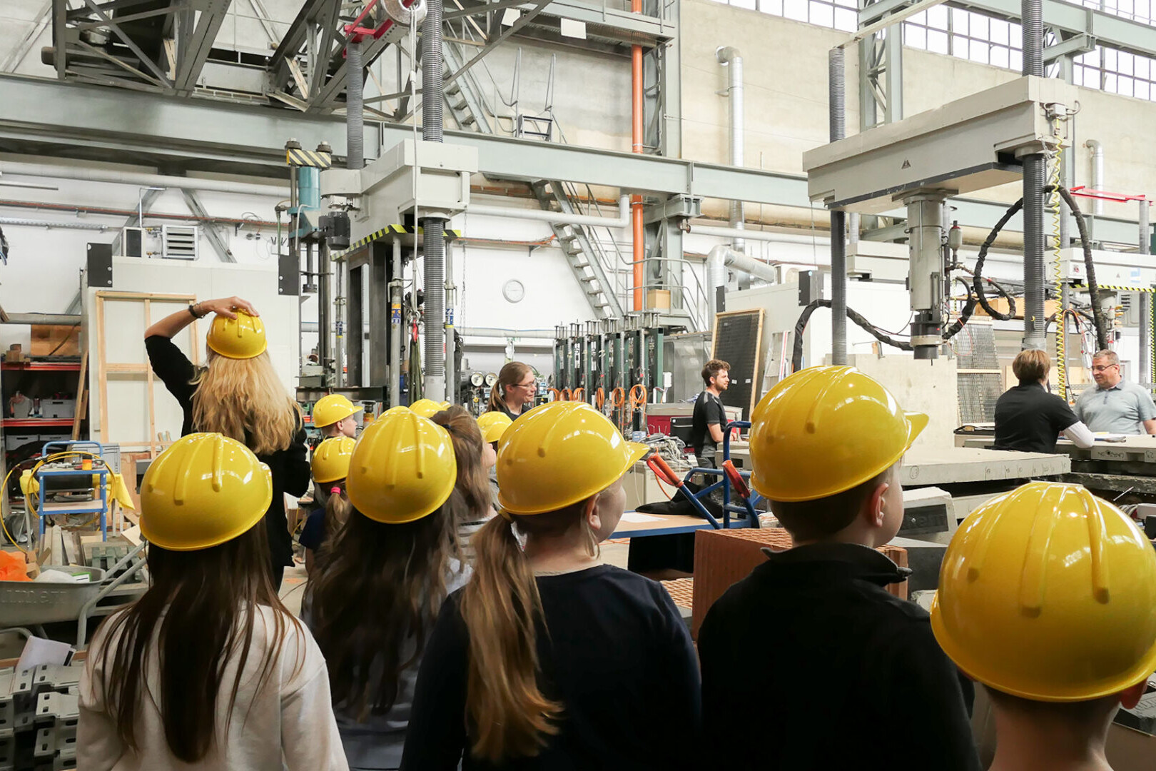 Hortkinder mit gelben Bauhelmen vor Prüfgeräten